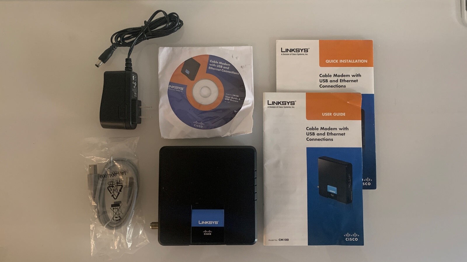 Cisco Linksys CM100 Cable Modem with power adapter, 2 manuals, CD, USB cable